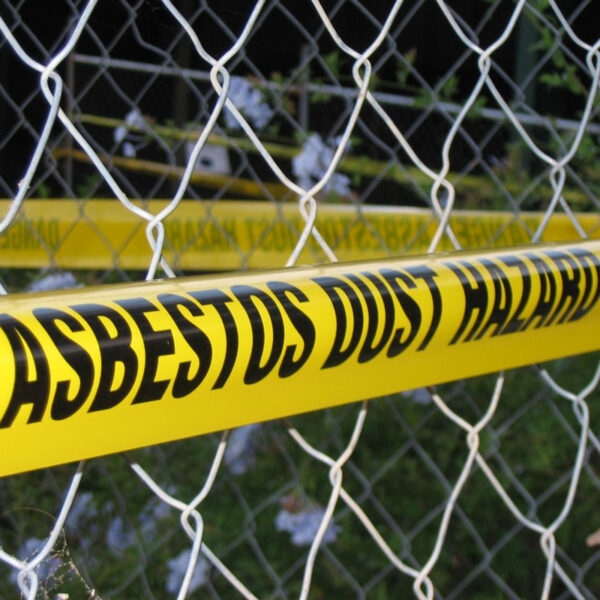 Caution tape with 'ASBESTOS DUST HAZARD' text as a warning in a restricted area