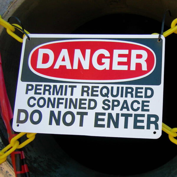 Danger sign warning against entry without a confined space permit in front of a dark opening