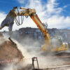 Excavator demolishing a building, showcasing the need for demolition safety permits