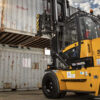 Forklift lifting a large cargo container, demonstrating the importance of safety permits in operation