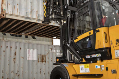 Forklift lifting a large cargo container, demonstrating the importance of safety permits in operation