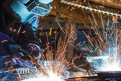 Welder performing hot work with sparks flying, under safety permit regulations