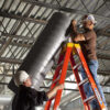 Two technicians working on HVAC ducting using a ladder, complying with ladder safety regulations