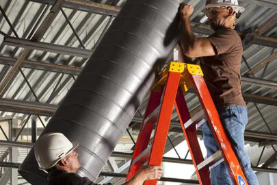 Two technicians working on HVAC ducting using a ladder, complying with ladder safety regulations