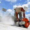 Construction worker using a concrete saw while dust clouds form, highlighting the need for silica dust safety permits