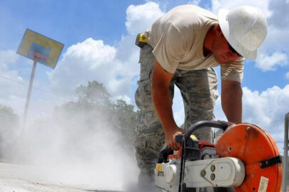 Construction worker using a concrete saw while dust clouds form, highlighting the need for silica dust safety permits